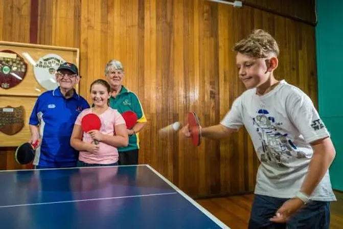 A junior player rallies while senior members watch on